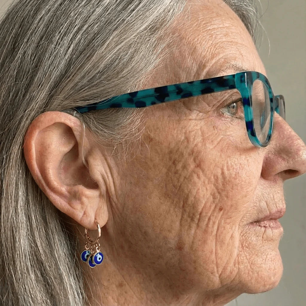 Close-up of an elderly woman wearing blue eyeglasses with a neutral background